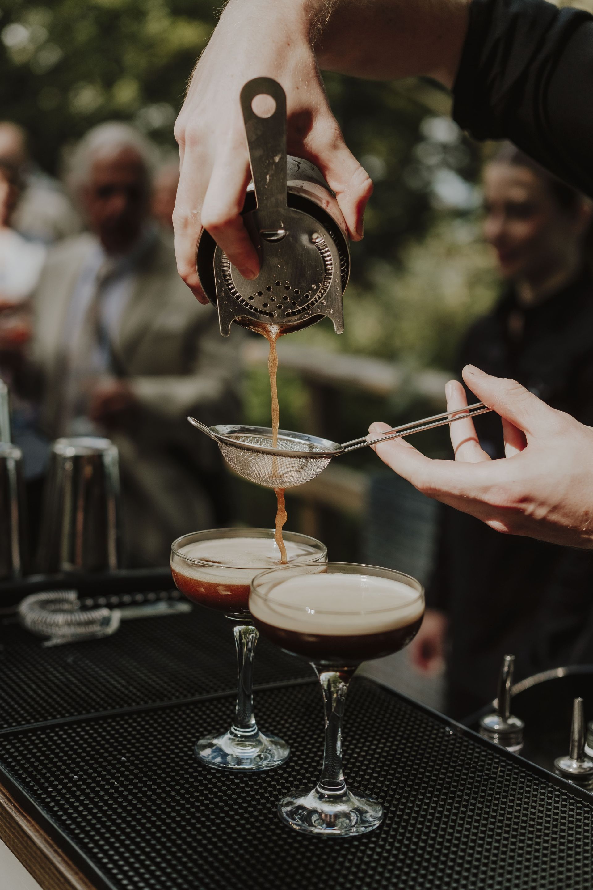 Bartender pouring espresso martinis at an outdoor event.