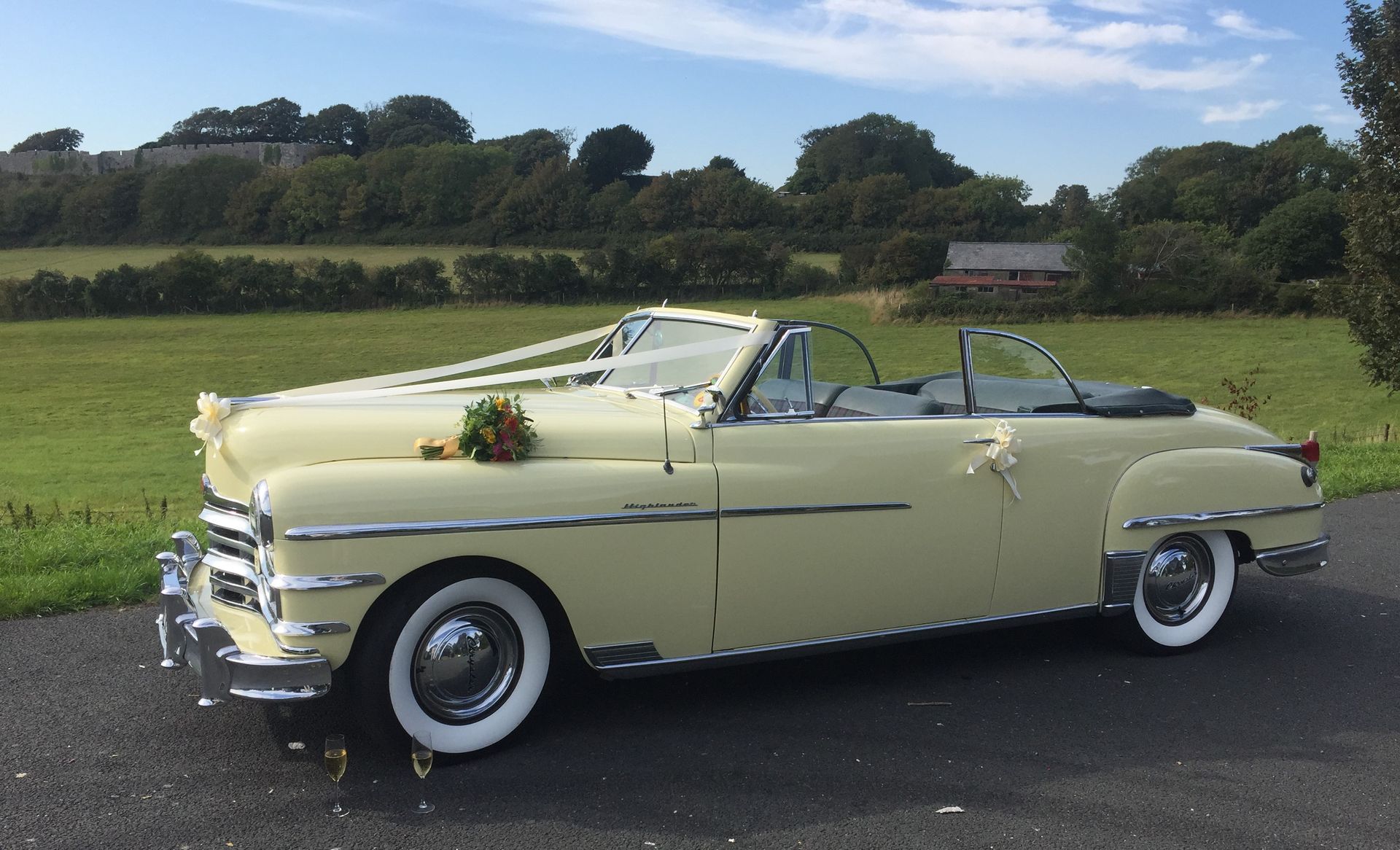 Yellow vintage convertible decorated for a wedding, parked on asphalt.