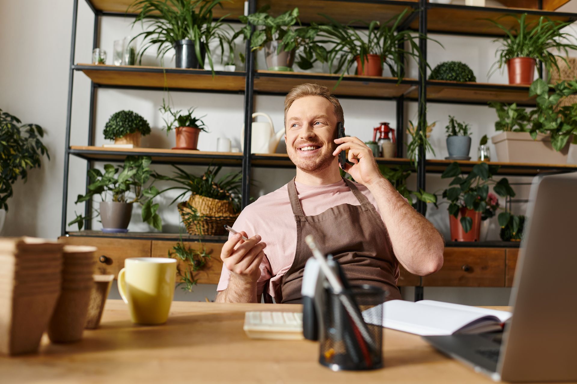 A man is sitting at a desk talking on a cell phone.