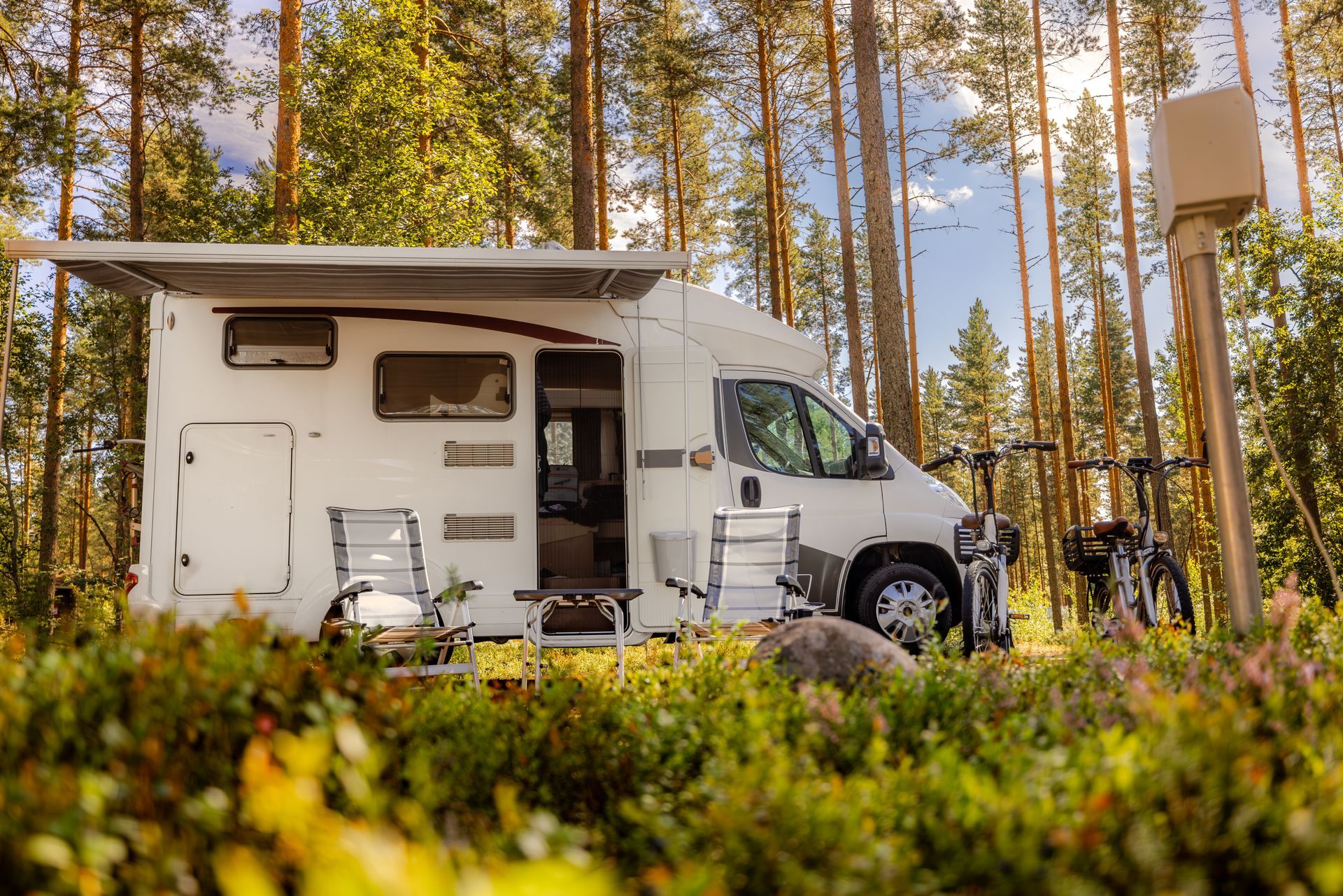 A white rv is parked in the middle of a forest.