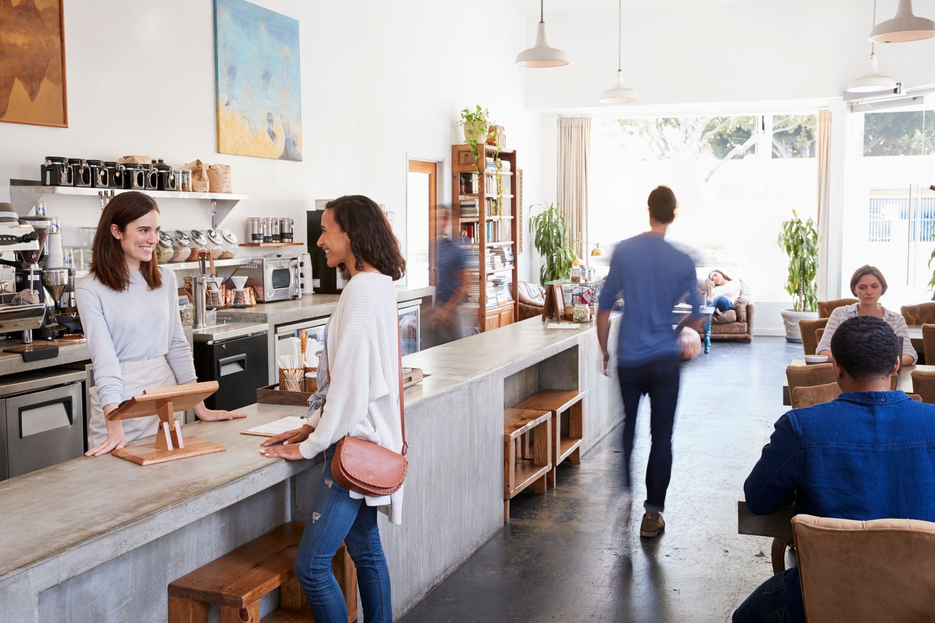 A woman is standing at a counter in a restaurant talking to a customer.