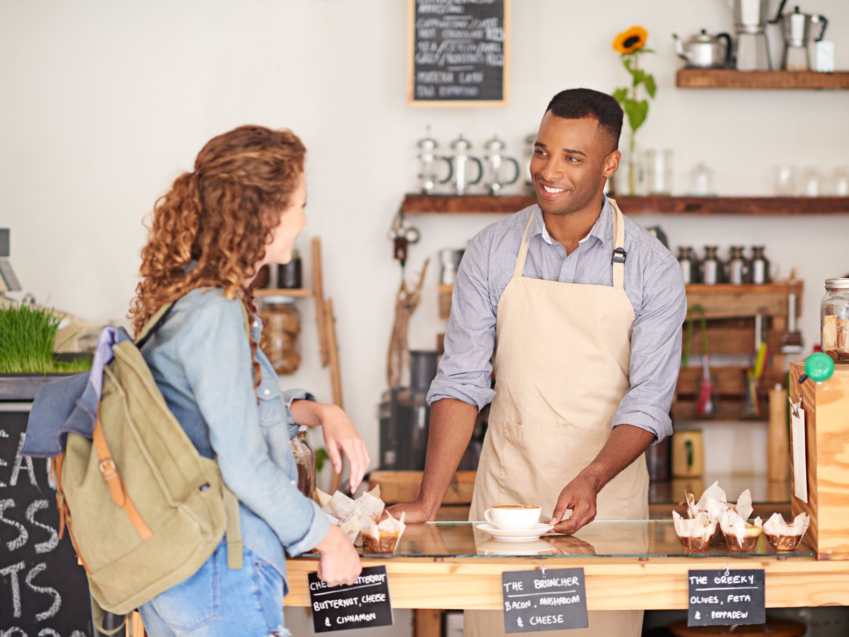 A man is serving a woman a cup of coffee in a cafe.