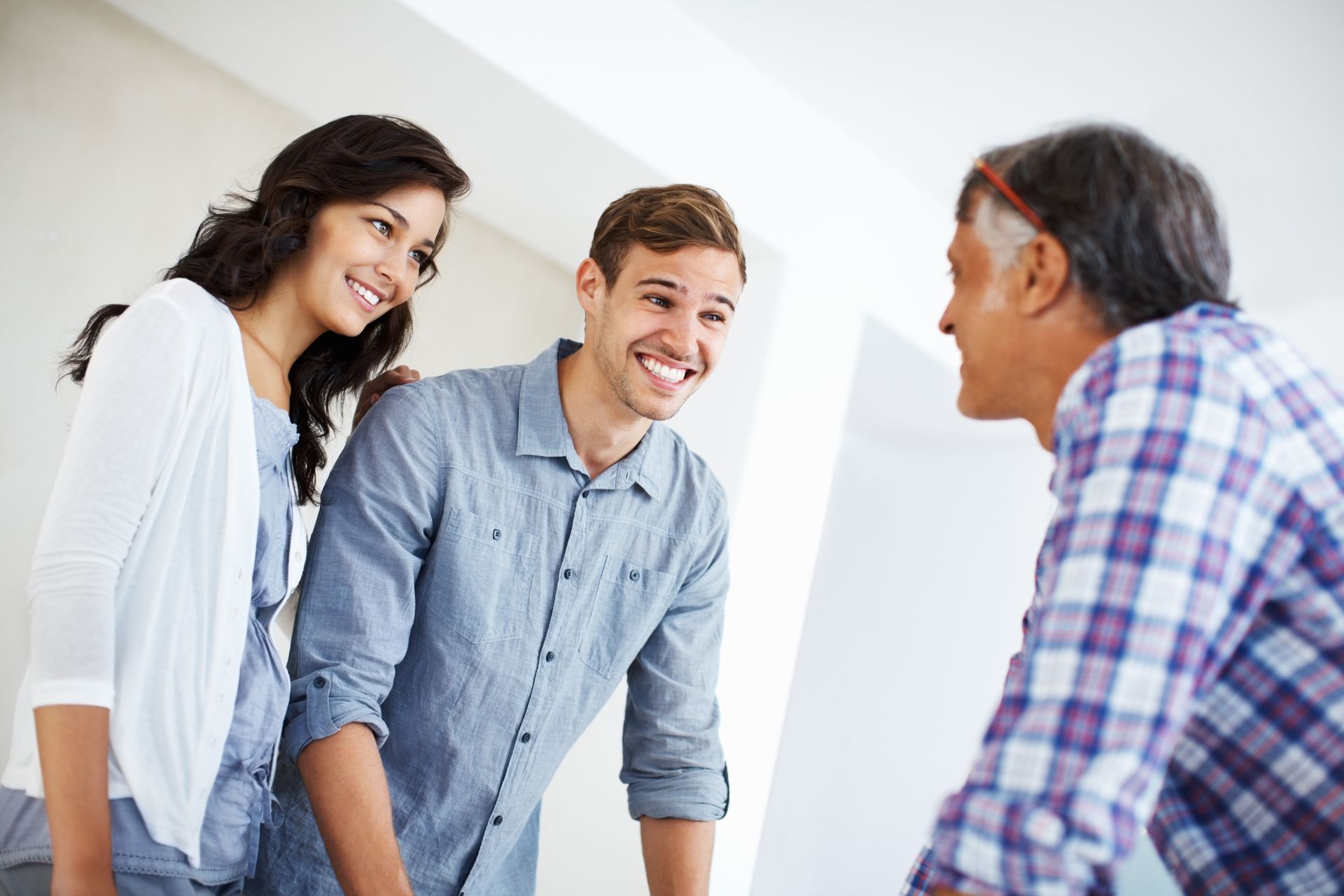 A man and a woman are standing next to each other talking to a man.