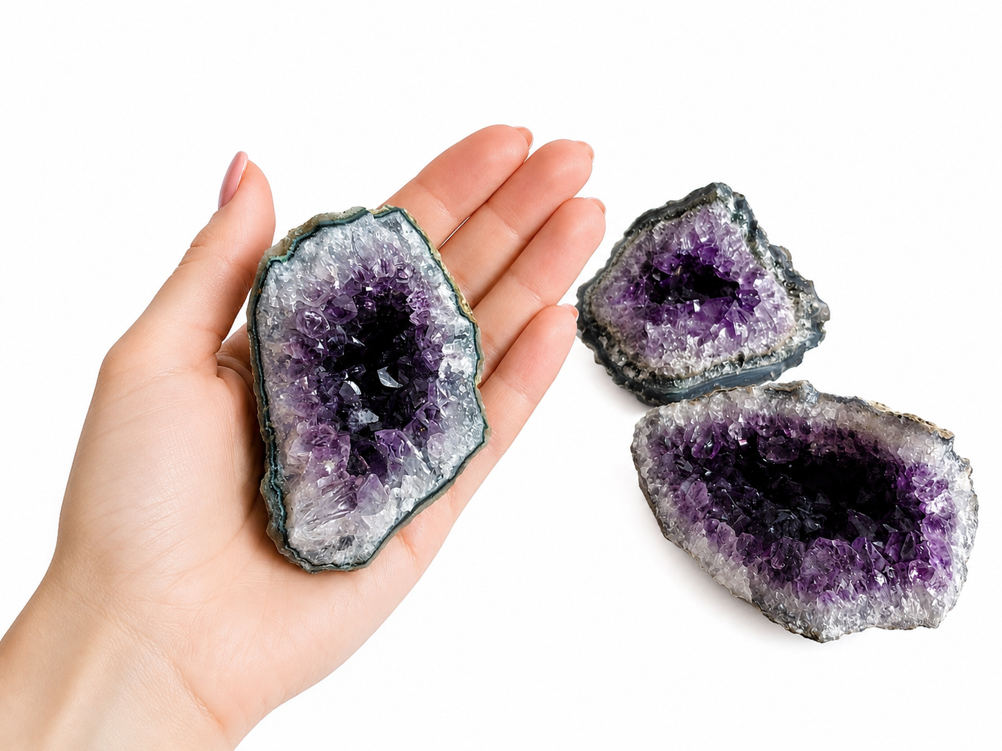 Paarse amethistgeode met een sprankelend kristal in het midden op een witte achtergrond.