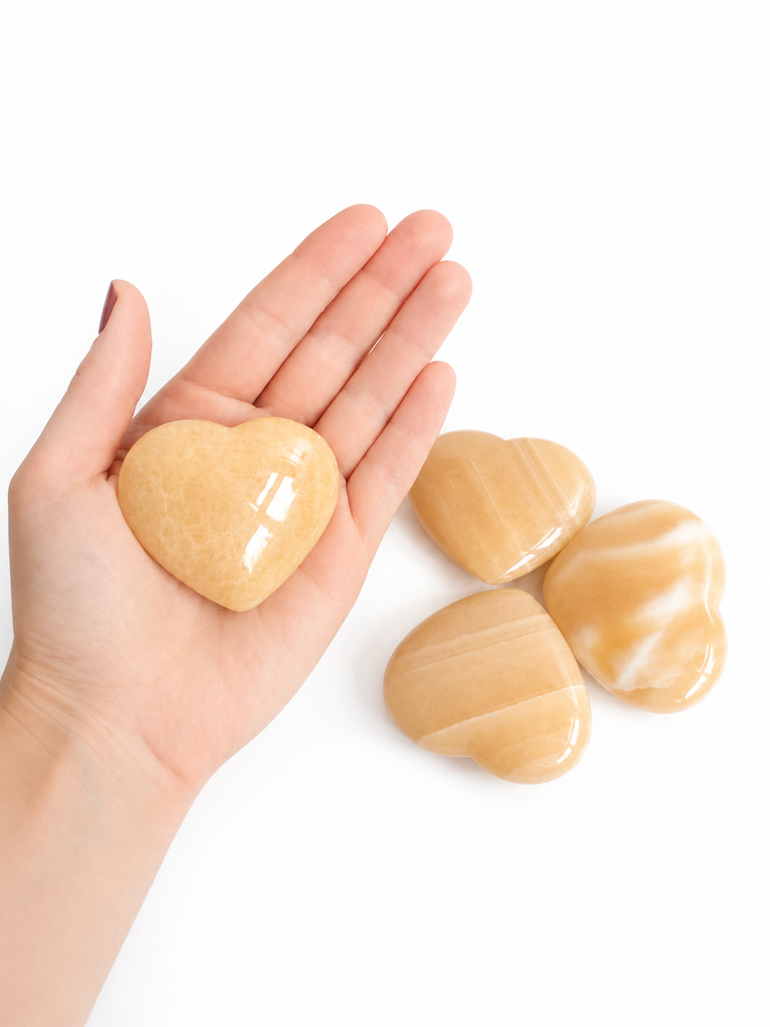 Vier beige hartvormige stenen, gerangschikt in een klaverpatroon op een witte achtergrond.