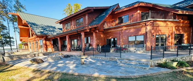 Rustic red wooden lodge with outdoor patio tables in a sunny mountain setting