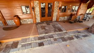 Log cabin entrance with double wooden doors, stone path, and a brown urn on the porch