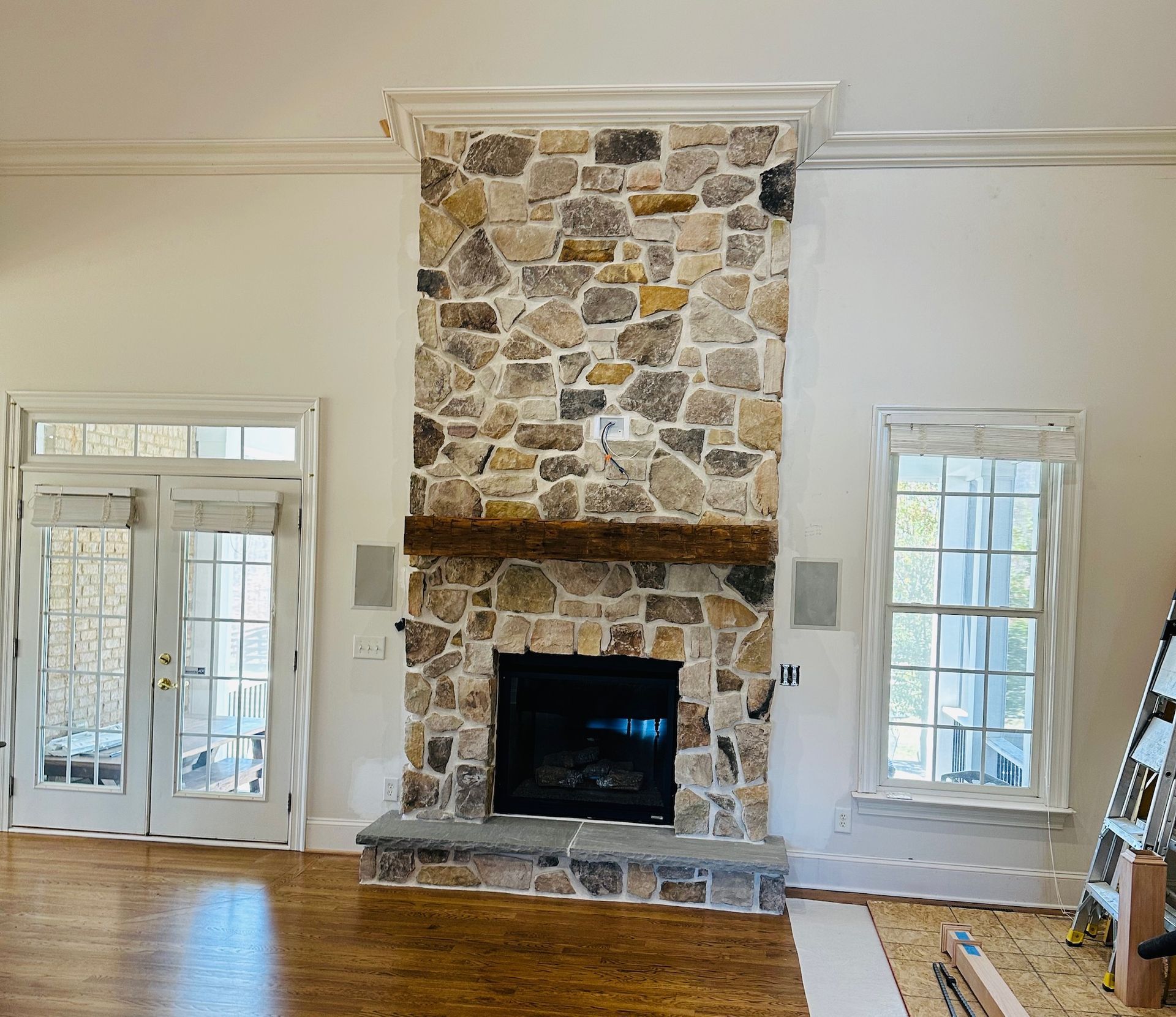 Bright living room with a stone fireplace, tall windows, and hardwood floors
