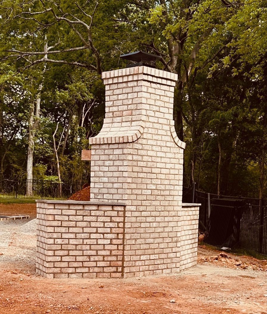 Outdoor brick barbecue or fireplace with chimney in a wooded yard