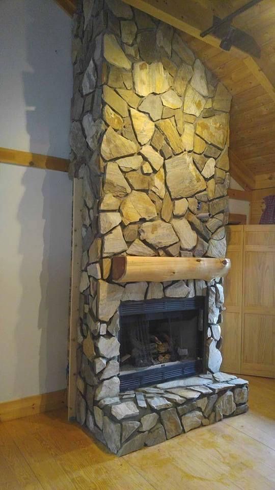Stone fireplace with a wooden mantel in a wood-floored room