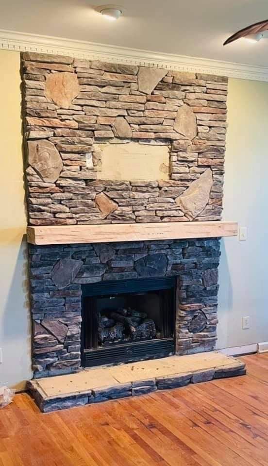 Stone fireplace with a mantel and stacked-stone surround on a hardwood floor.