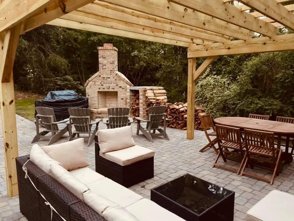 Covered patio with outdoor seating, fire pit, dining table, and brick fireplace