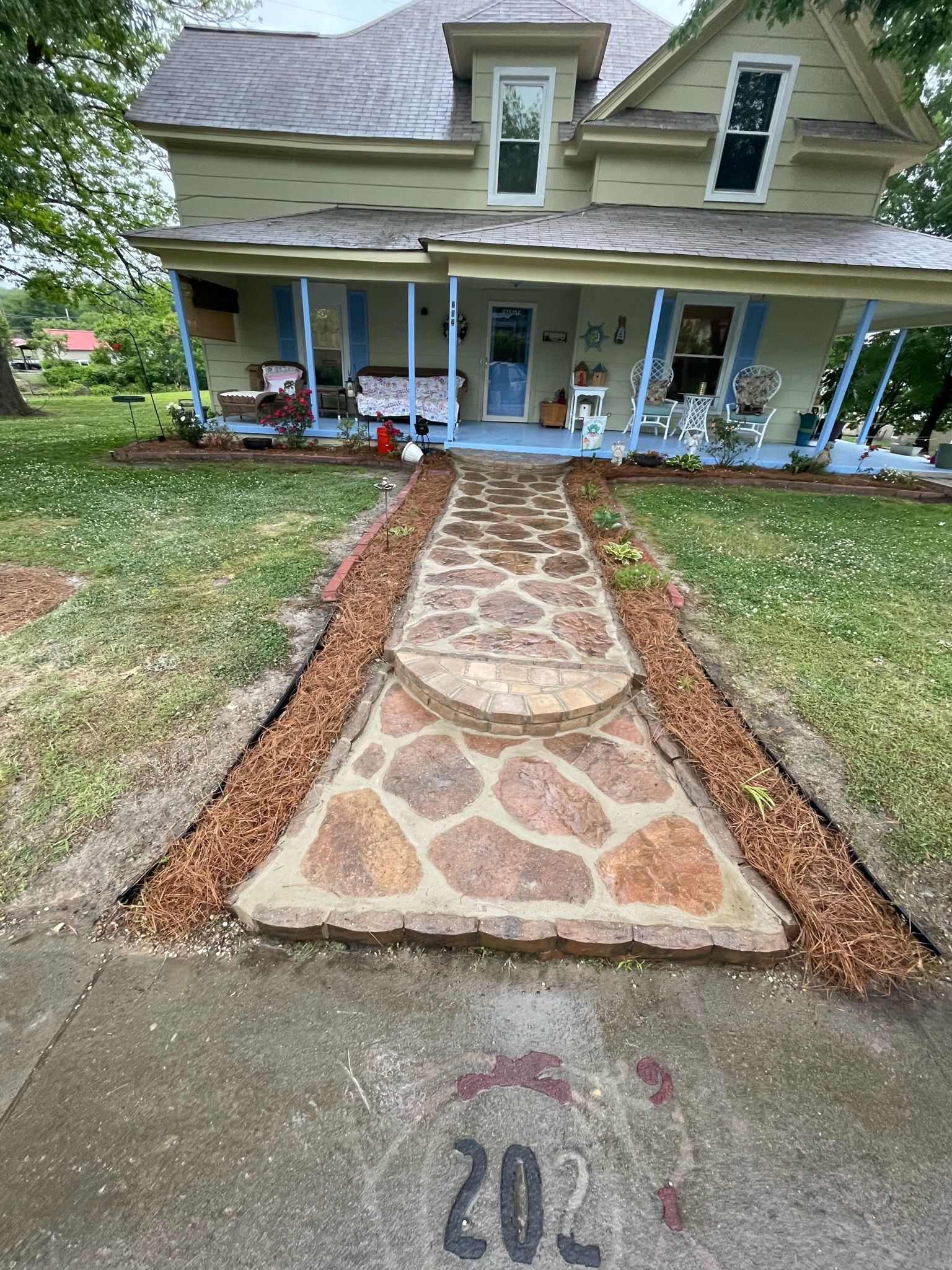 Front walkway with stone path leading to a porch on a pale green house