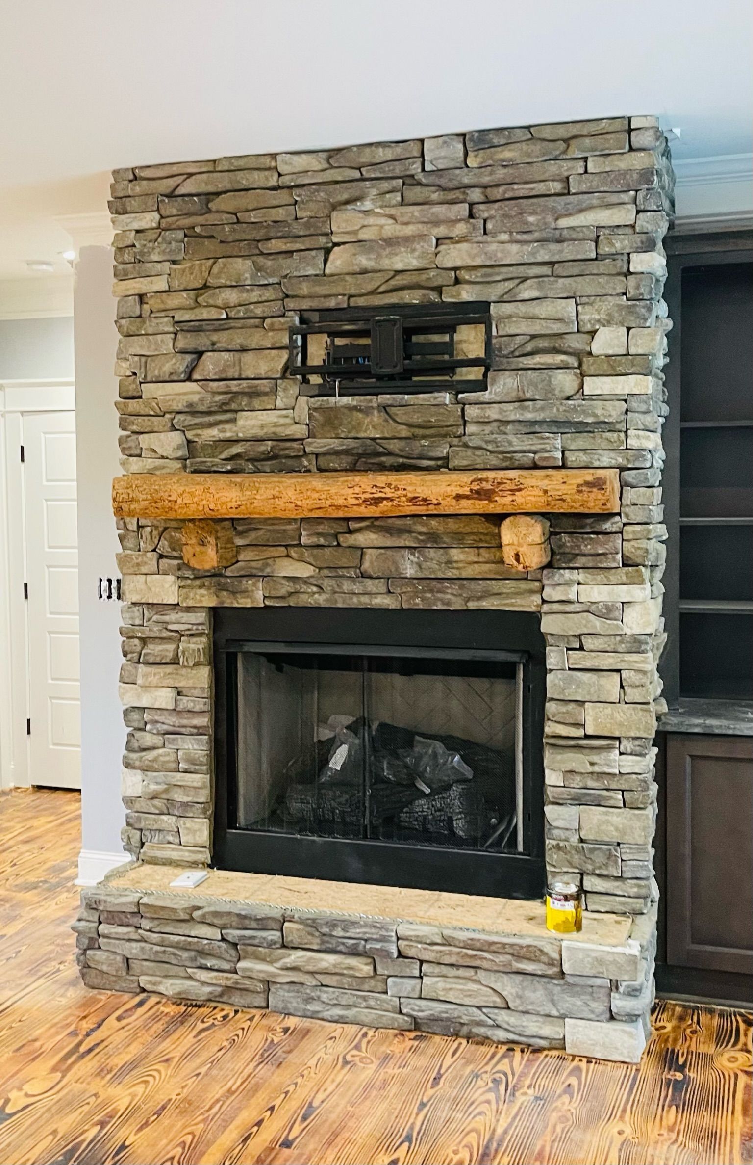 Stone fireplace with wooden mantel and black firebox in a living room
