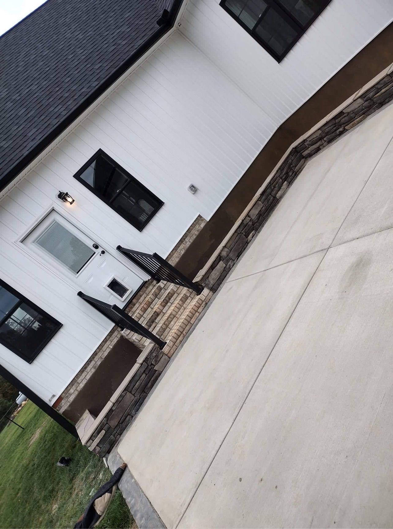 White house exterior with front door, windows, brick accents, and a paved driveway