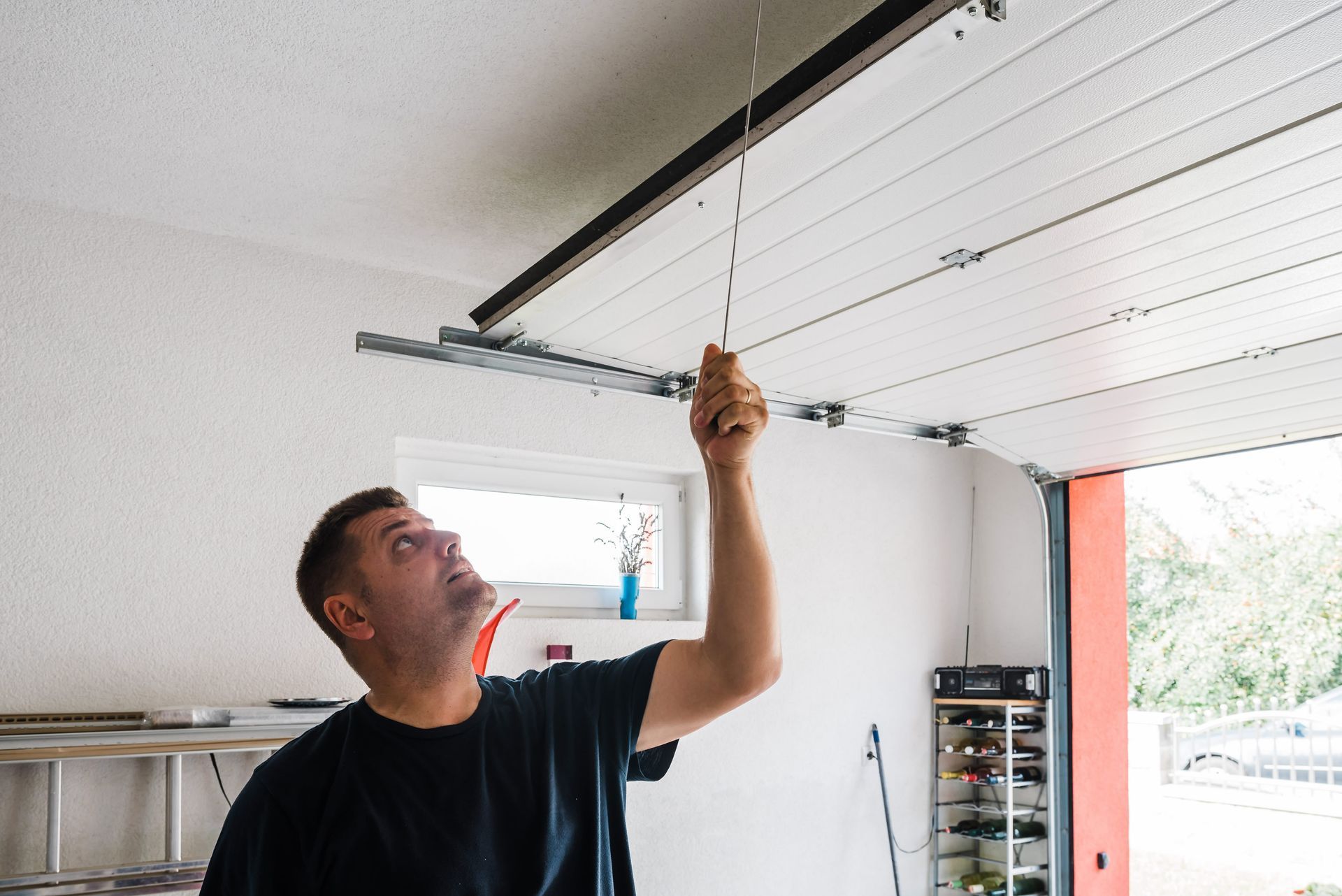 A man opens a PVC garage door manually indoors.