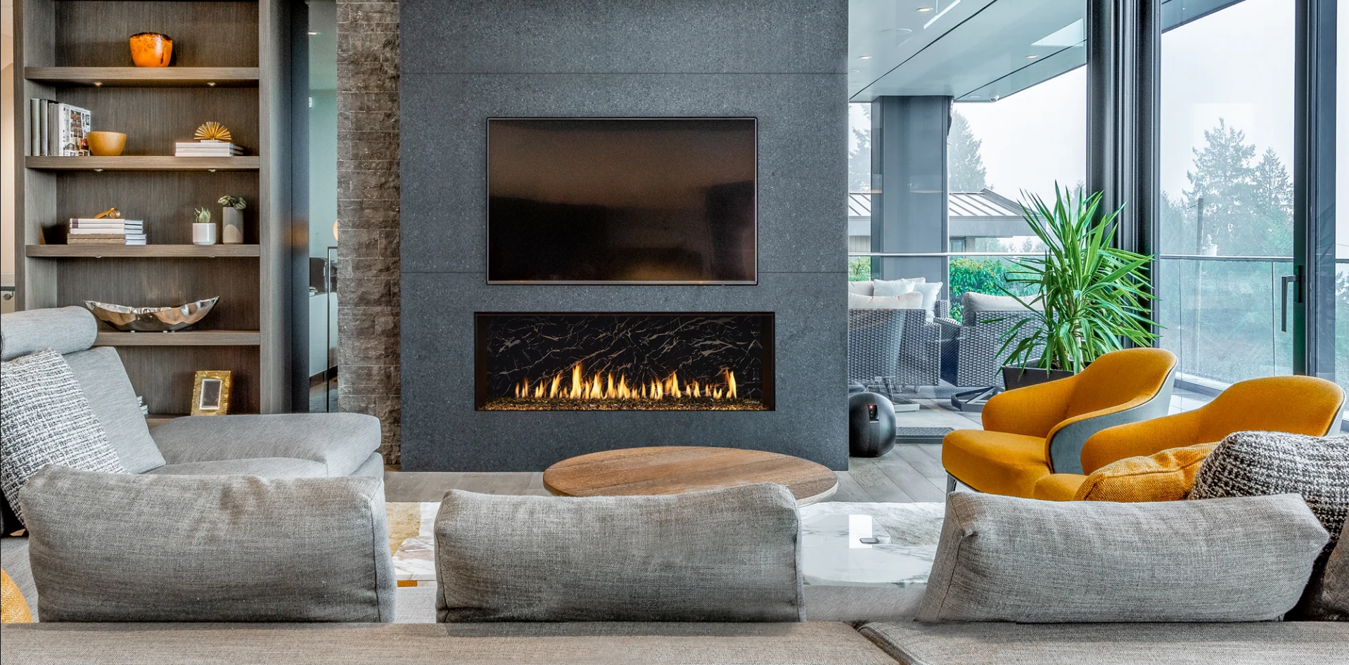 Living room with stone fireplace, TV, and modern furniture in front of a window.