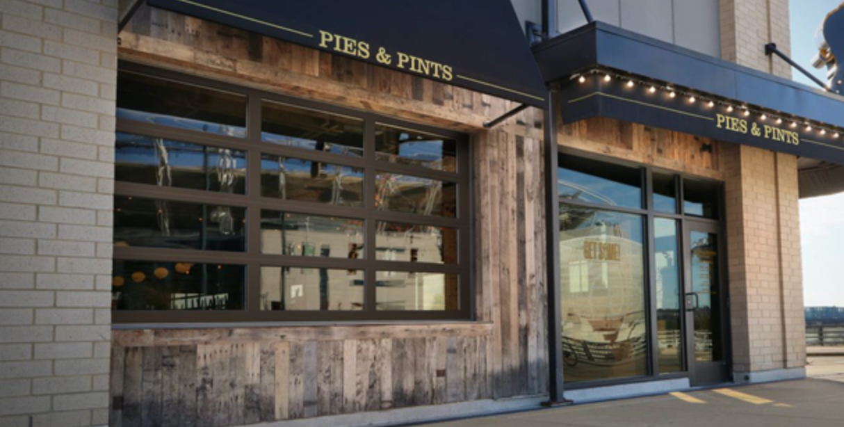 Pies & Pints restaurant exterior with wooden siding, black awning, and large windows.