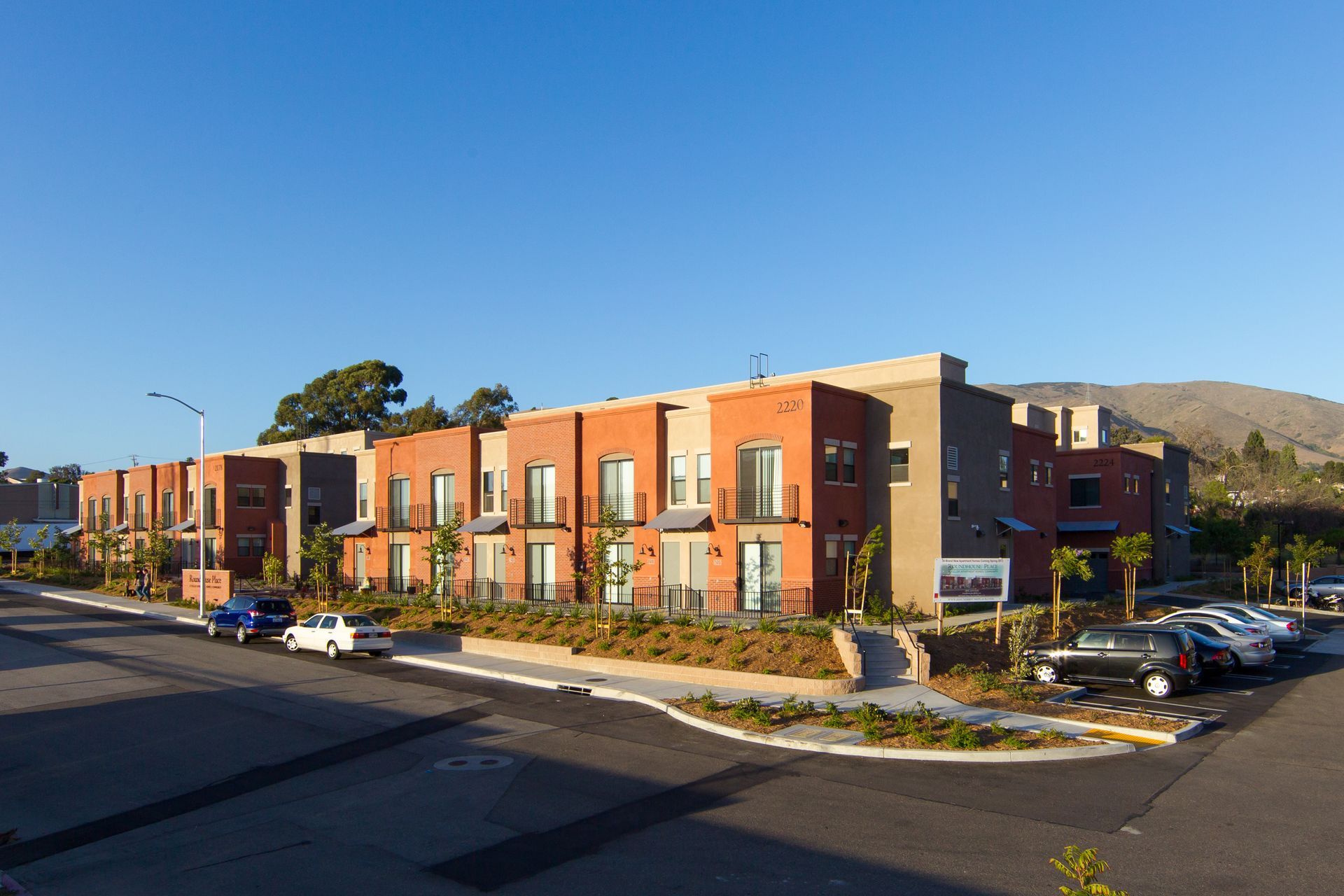 A row of apartment buildings with cars parked in front of them