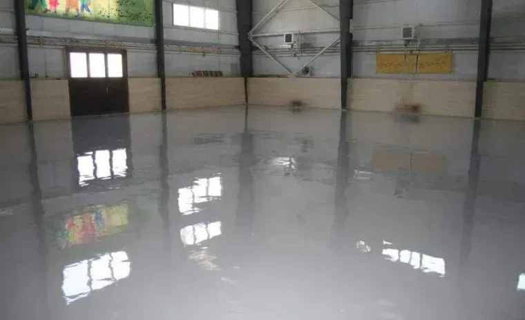Shiny, light gray floor reflecting windows and a door inside a large, empty building. Shiny, light gray floor reflecting windows and a door inside a large, empty building.