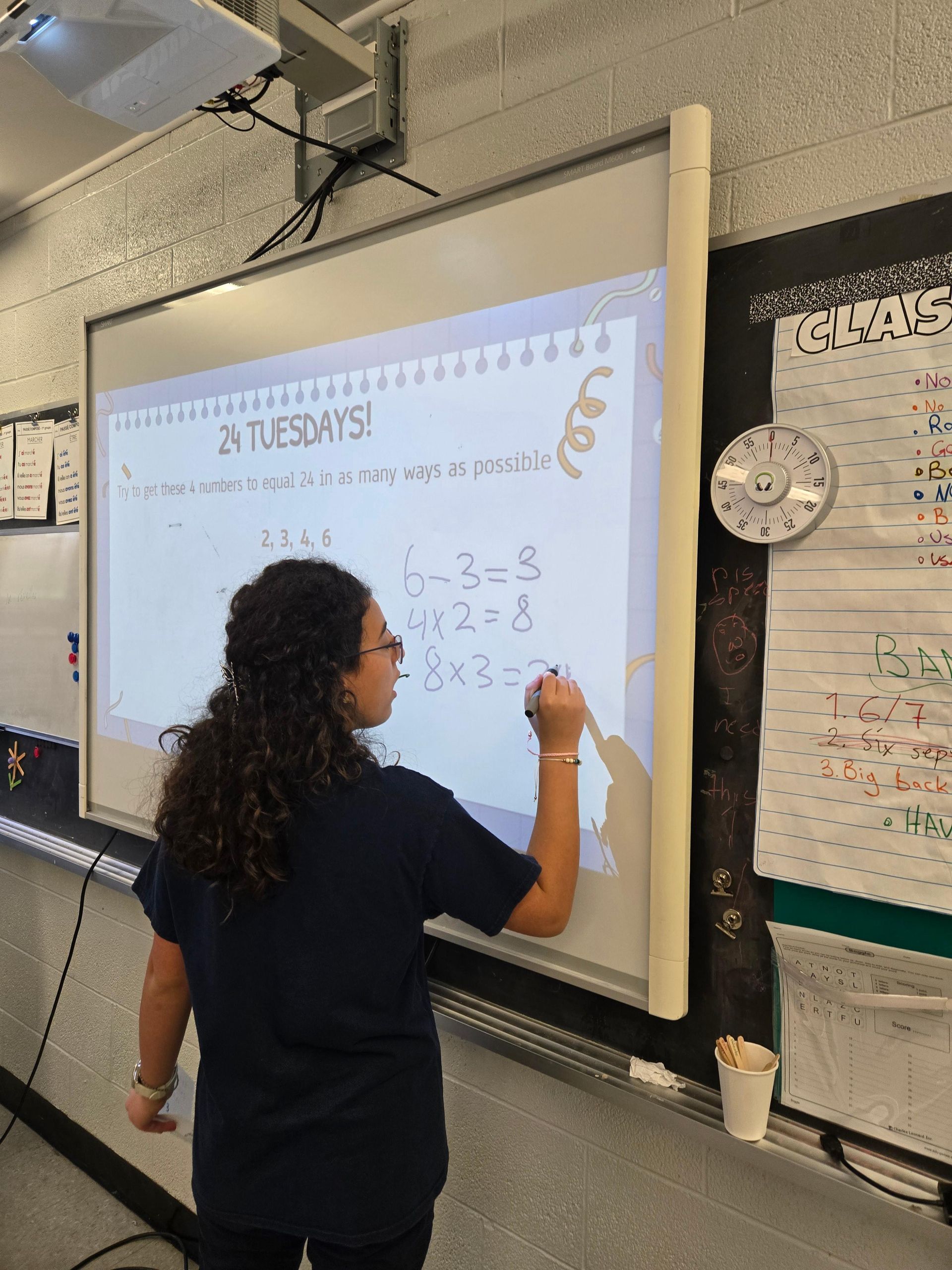 Teacher writing on a classroom whiteboard during a lesson.