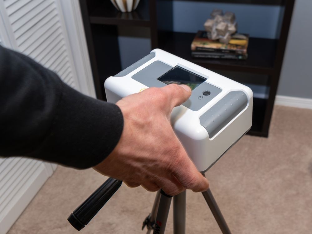 A man is holding a thermal camera in front of a toilet.