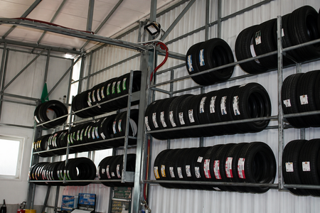 File di pneumatici impilati su scaffalature metalliche all'interno di un magazzino o di un'officina di pneumatici.