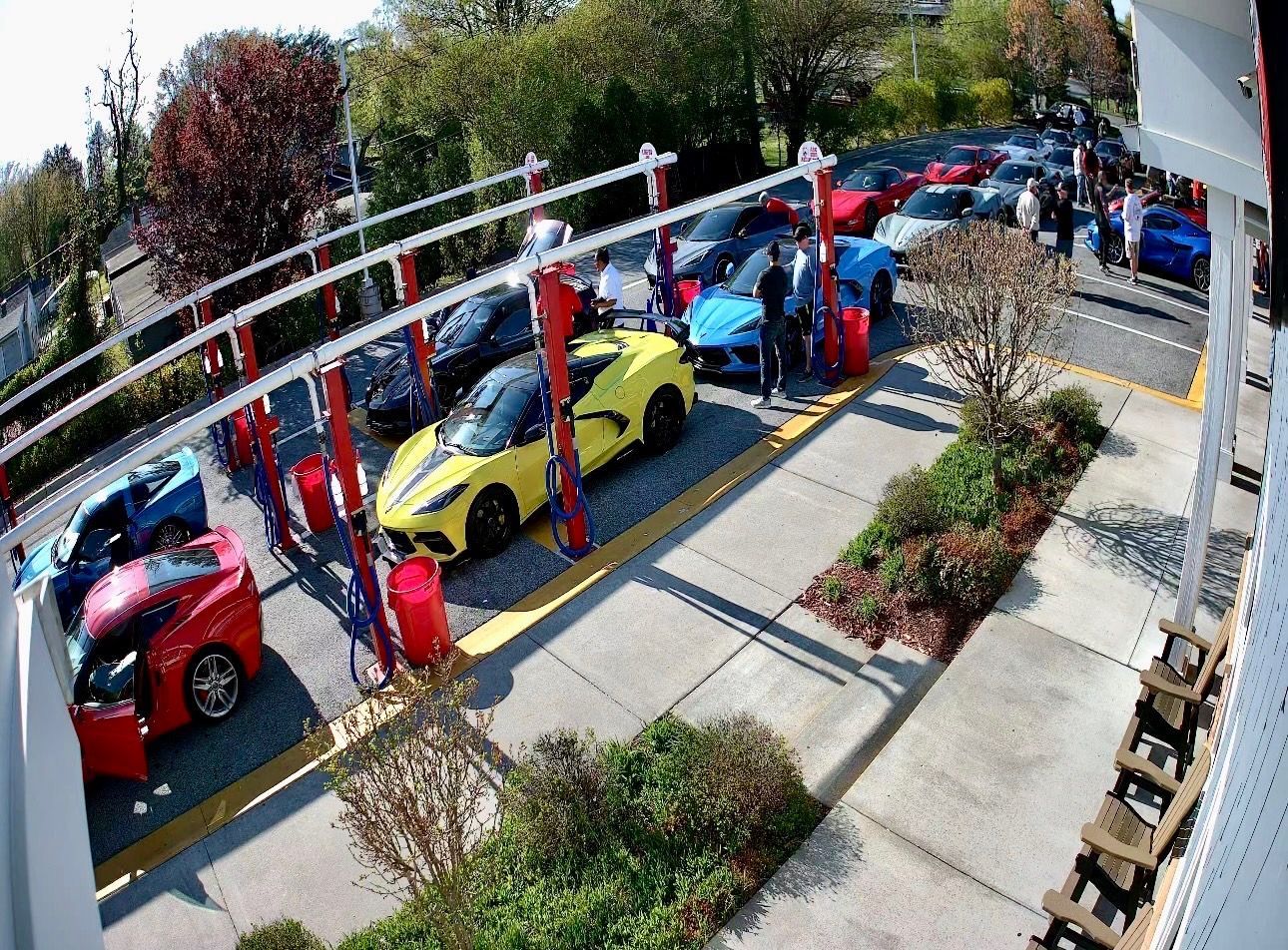 Outdoor car lot with colorful cars parked under a white canopy on a sunny day