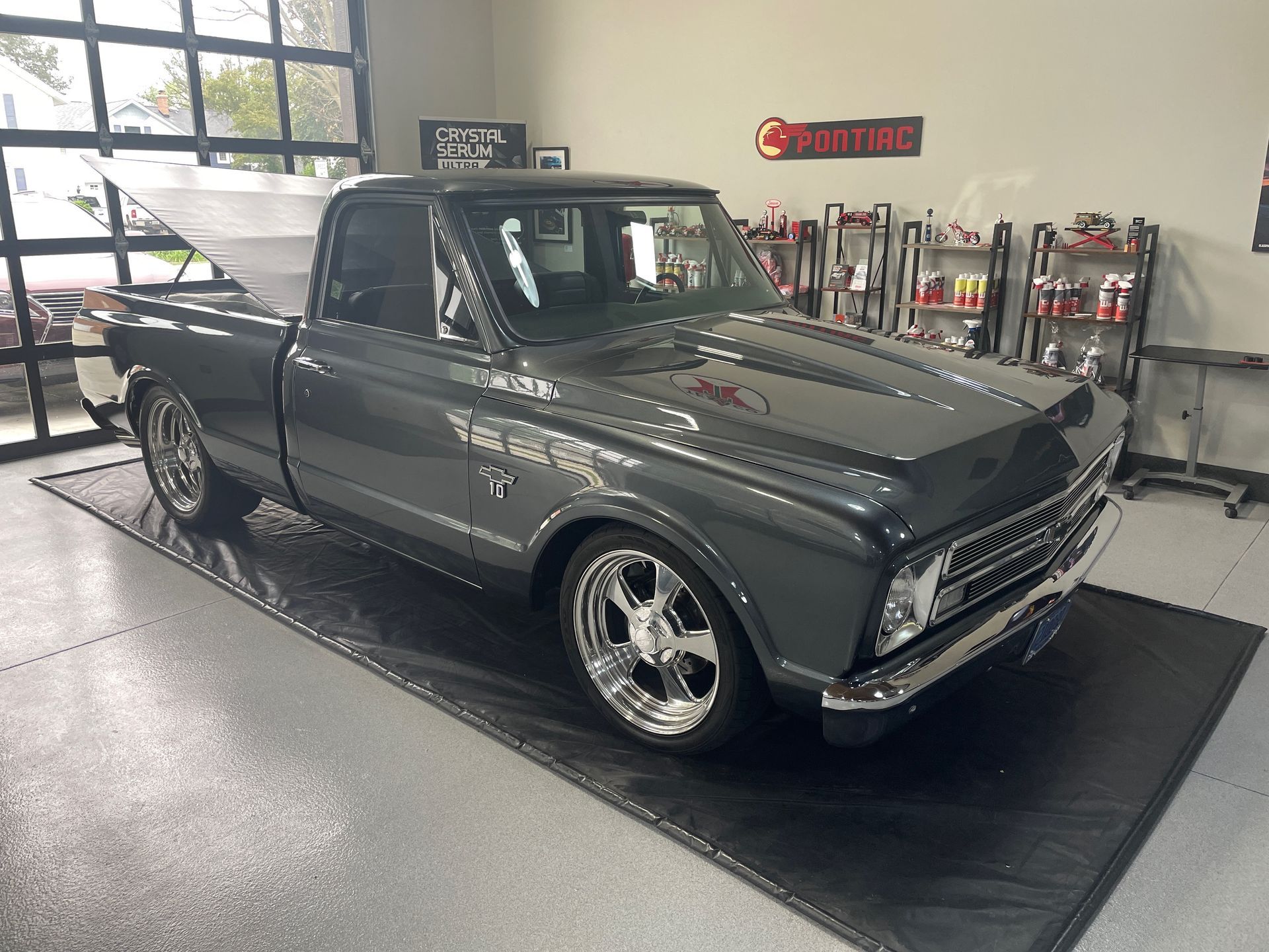 Gray vintage Chevy pickup truck on a black mat in a garage with detailing supplies.