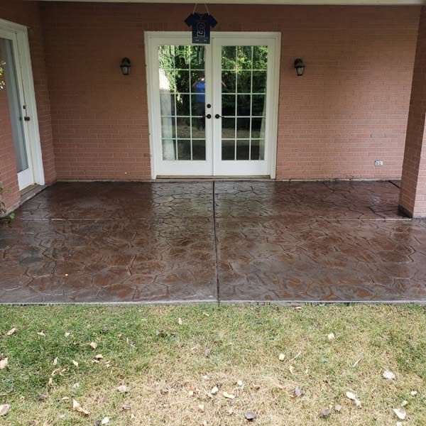 Covered porch with stamped concrete floor, brick wall, and white French doors.