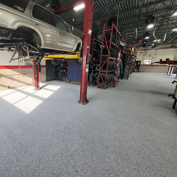 Auto repair shop with a car on a lift and a freshly coated gray floor