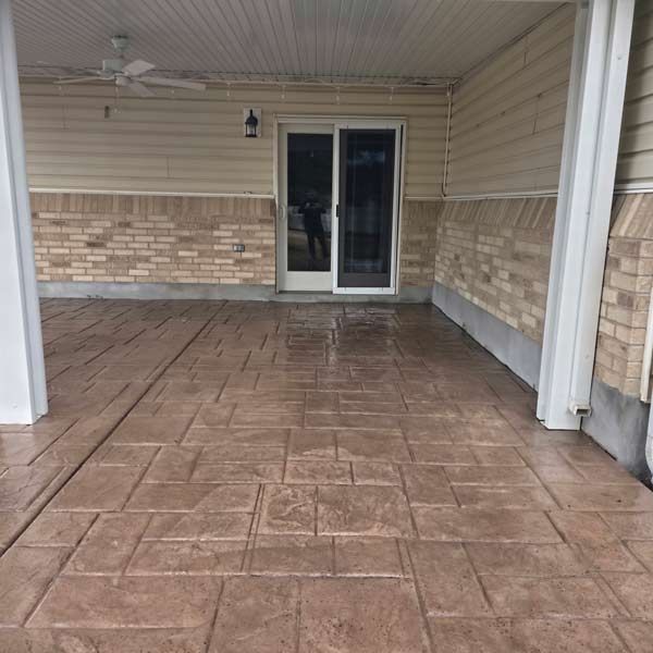 Covered patio with stamped concrete floor, brick walls, and sliding glass doors