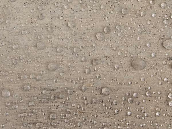 Close-up of a beige textured surface covered in water droplets