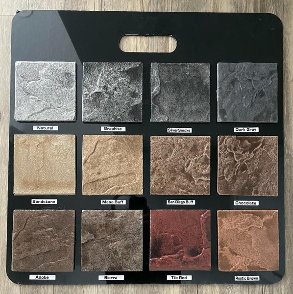 Black display board with 12 labeled square material samples in gray, tan, brown, and red tones.