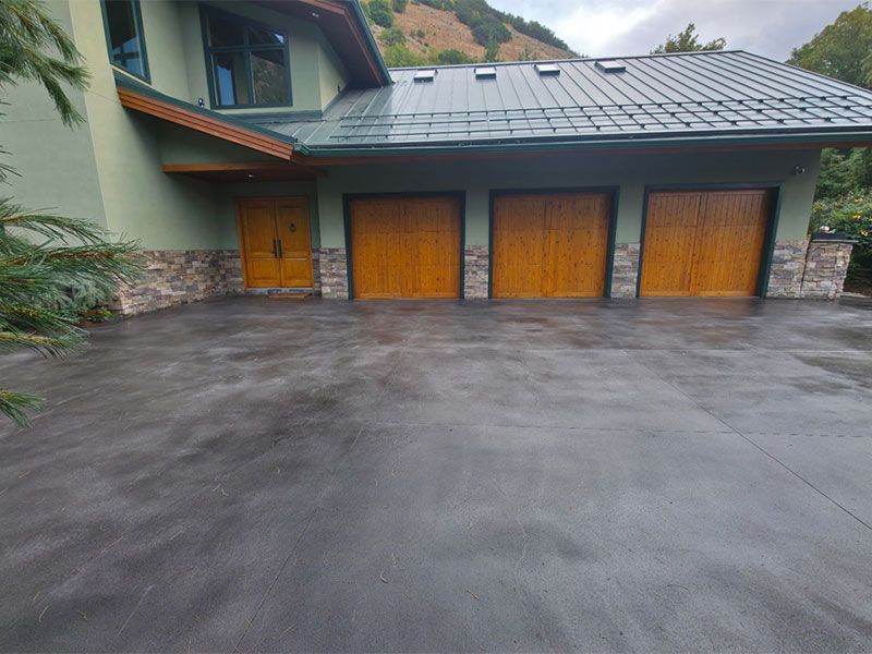 Modern house exterior with three wooden garage doors and a wet concrete driveway