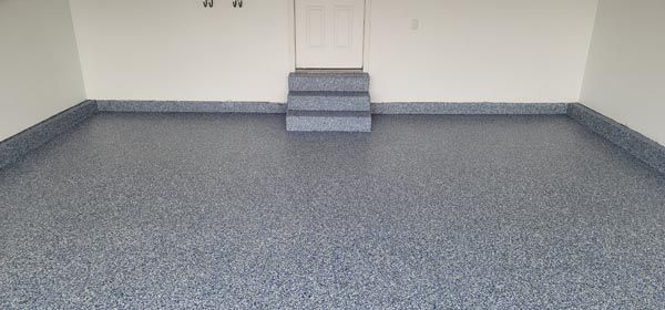Empty gray carpeted room with white walls and a small raised step at the far end