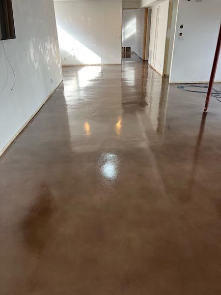 Empty hallway with glossy brown floor and white walls, lit by sunlight.