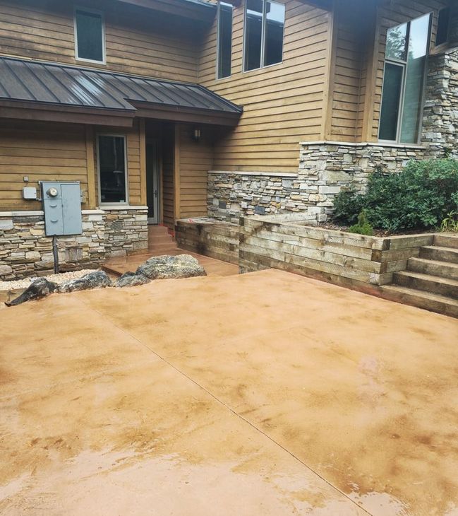 Tan house exterior with stone accents and a wet concrete patio in front