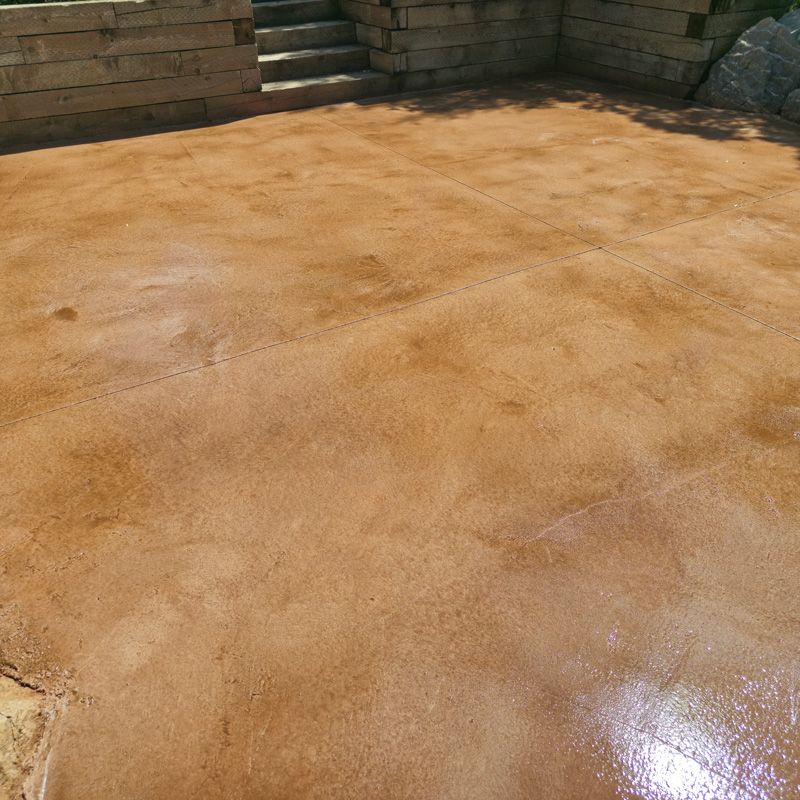 Wet tan stone patio with brick steps and wall in the background