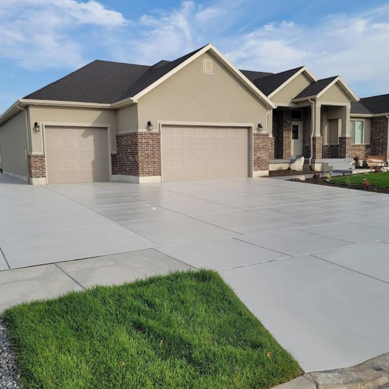 Suburban house with three-car garage and a wide concrete driveway under a blue sky