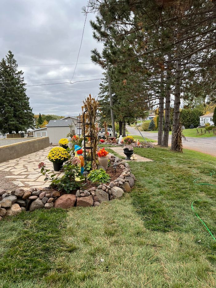 A garden with flowers and rocks along the side of a road.