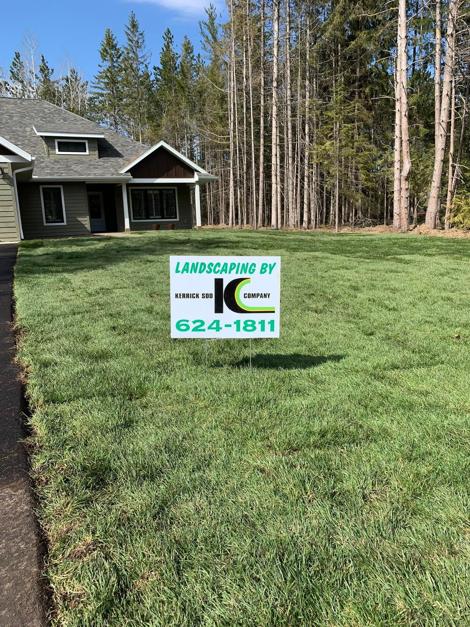 A house with a lush green lawn and a sign in front of it.