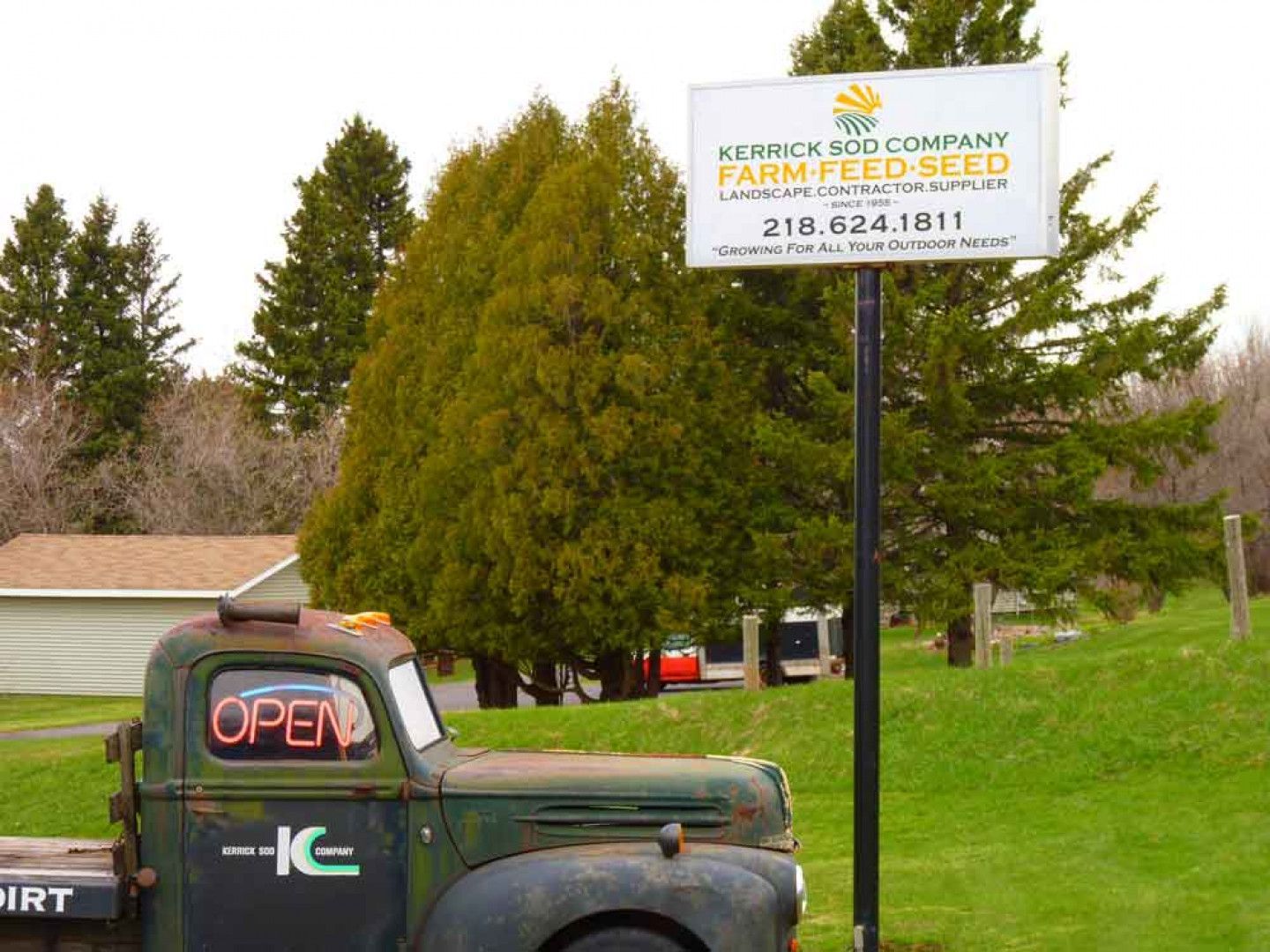 An old truck is parked in front of a sign that says farm feed seed