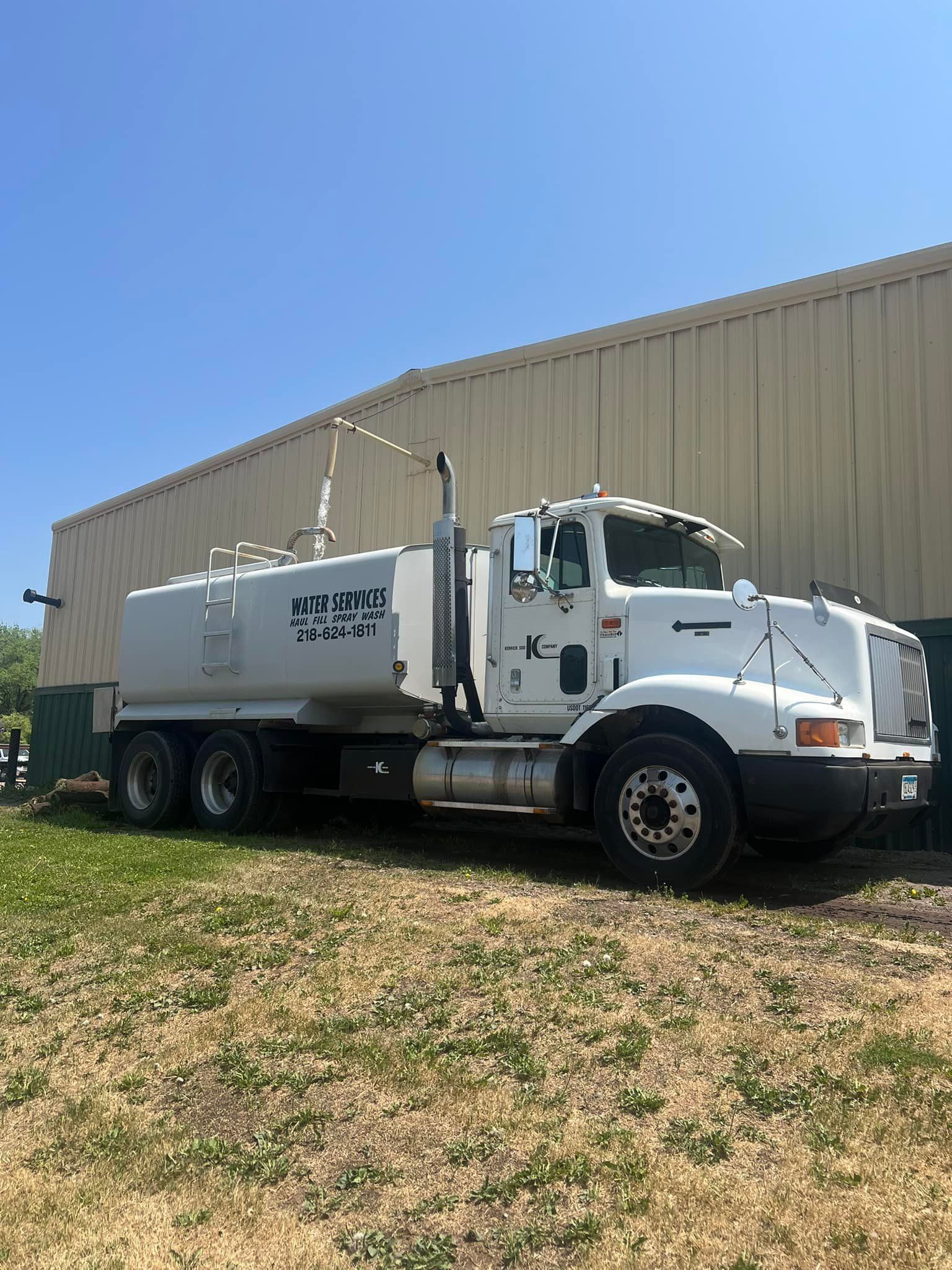 A white water truck is parked in front of a building.