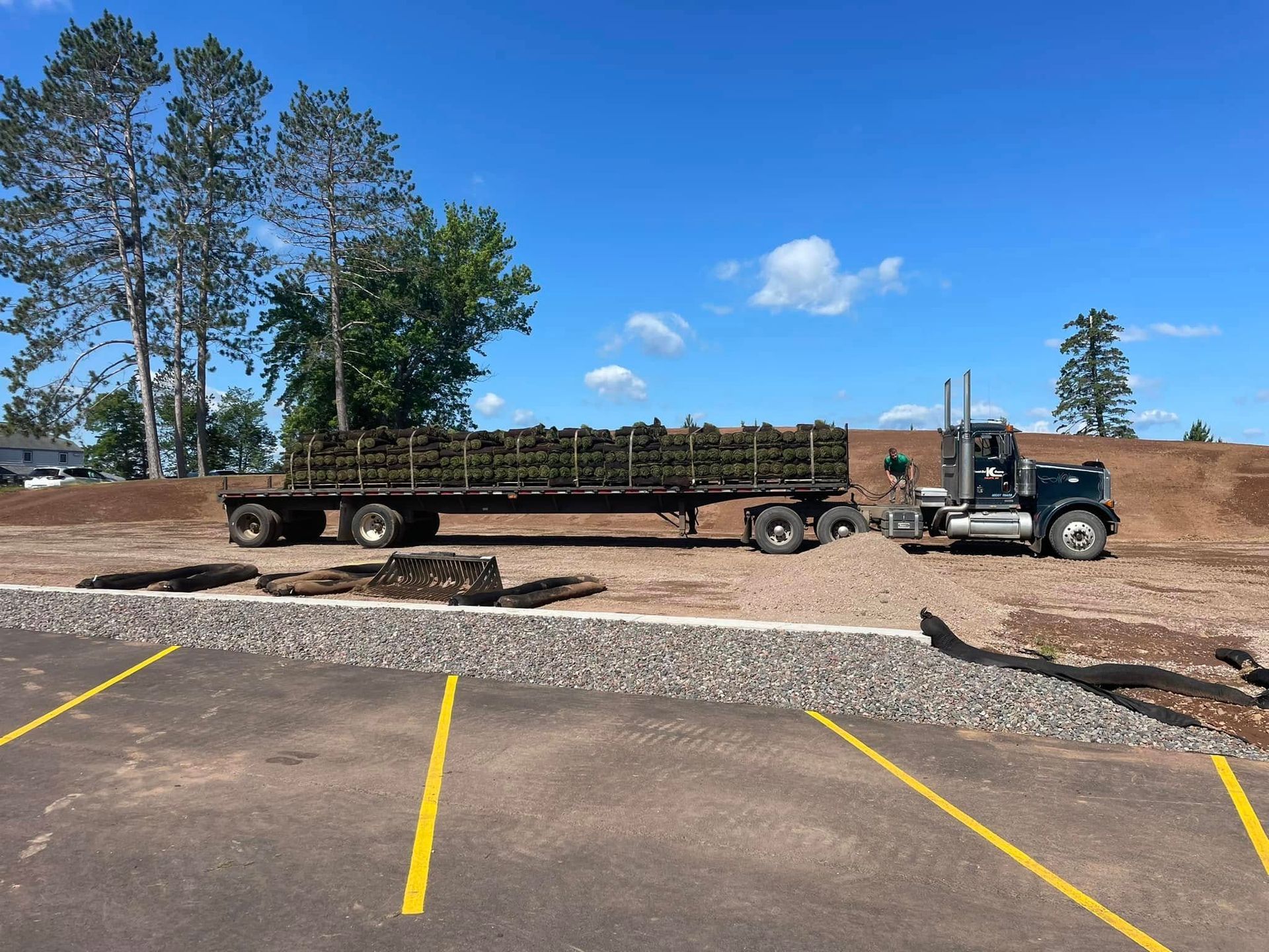 A semi truck is carrying a trailer full of grass.