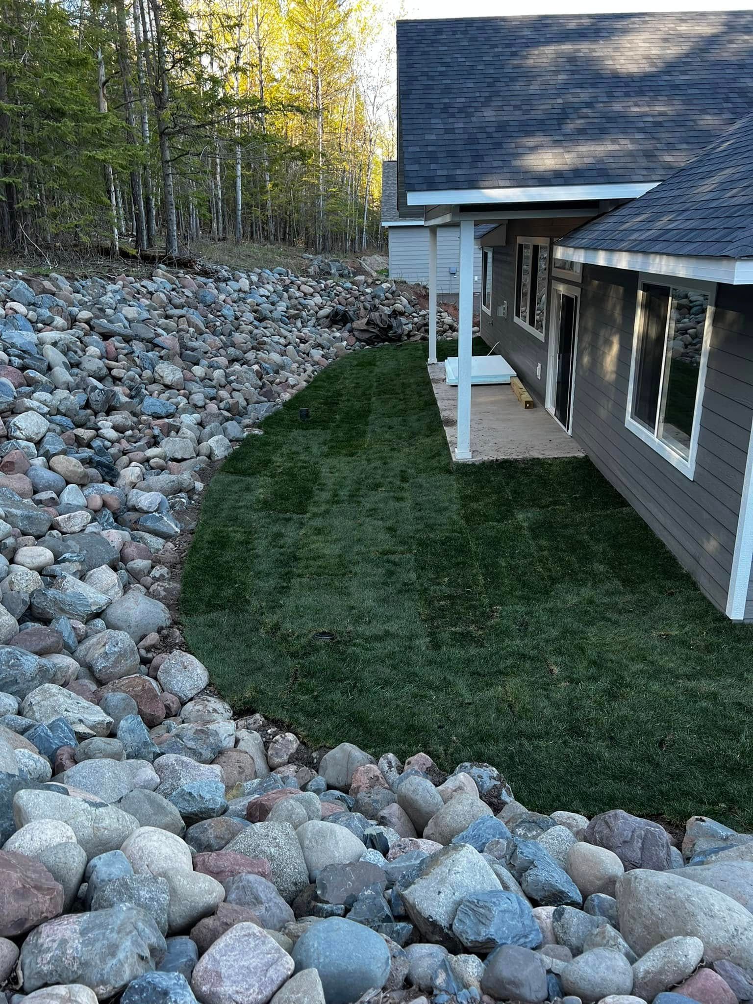 A house with a lot of rocks and grass in front of it.