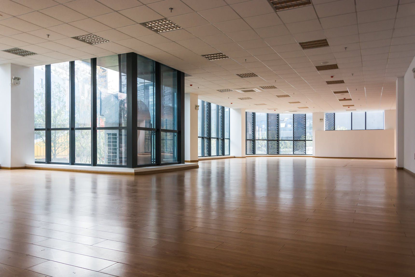 A large empty room with lots of windows and wooden floors.