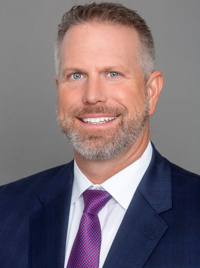 A man in a suit and tie is smiling for the camera.