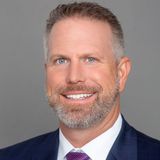 A man in a suit and tie is smiling for the camera.