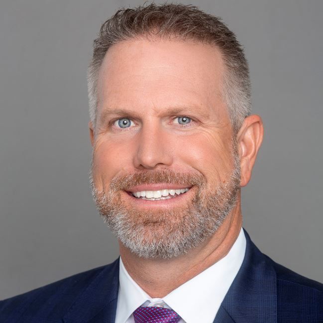 A man in a suit and tie is smiling for the camera.